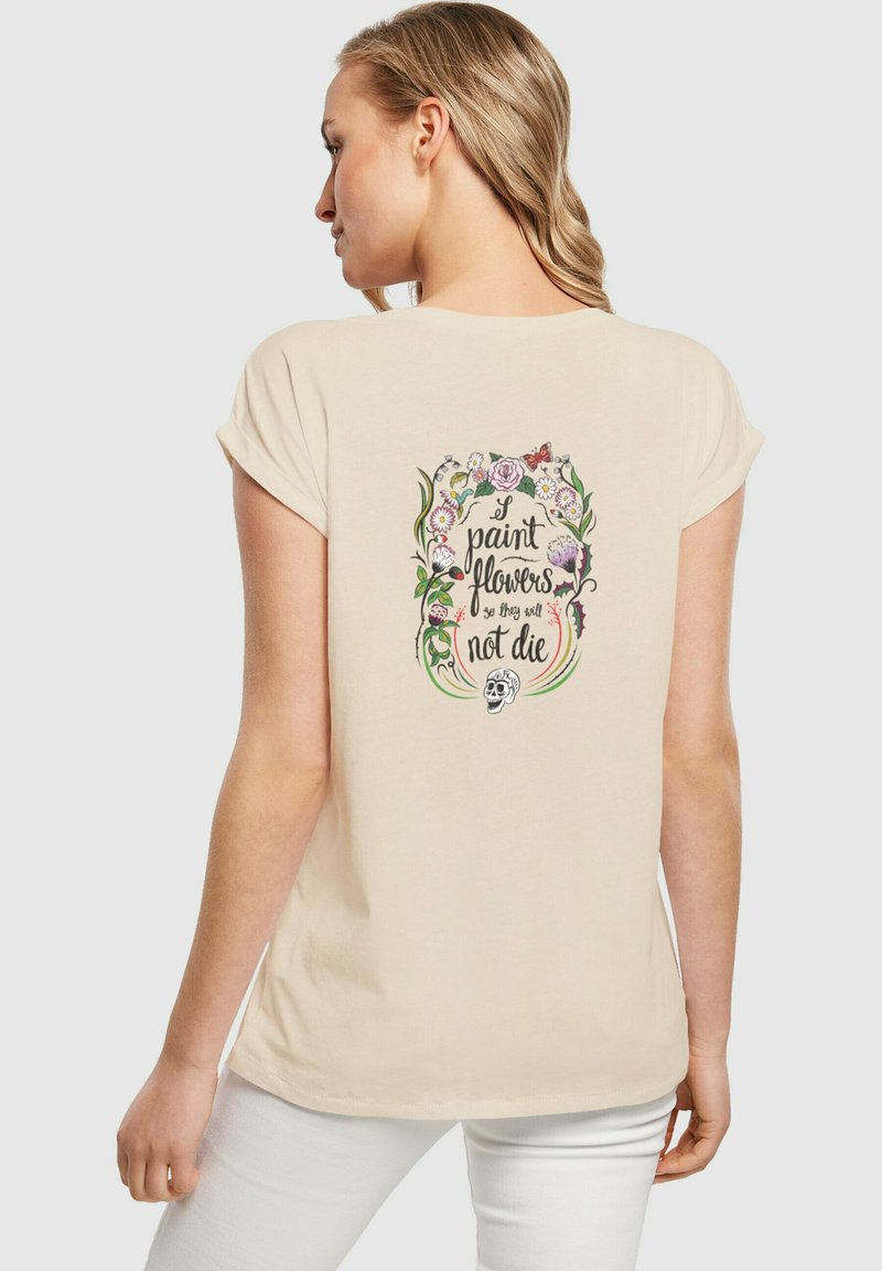 Beige T-Shirt mit kurzen Ärmeln, das ein buntes Blumenmotiv mit Text und einem Schädel auf dem Rücken zeigt. Weiches Material, lockere Passform.