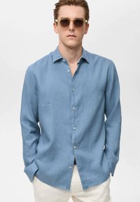 Light blue linen shirt with a button-down collar and long sleeves. Features a relaxed fit and buttons down the front.