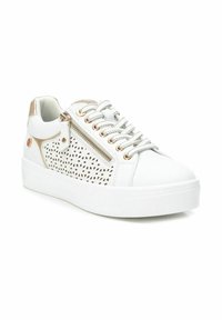 Zapatilla blanca con diseño perforado en los laterales, detalles metálicos dorados, cordones grises y un cierre decorativo en el lateral. Suela blanca gruesa.