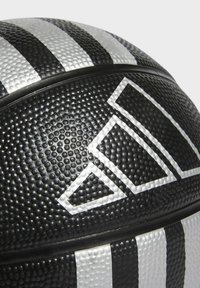 Balón de baloncesto negro con superficie texturizada, que presenta franjas y un logotipo blancos prominentes. El diseño incluye un patrón de puntos elevados para un mejor agarre.