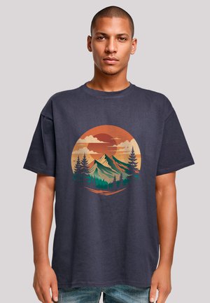 Navy blue cotton t-shirt featuring a circular mountain and sunset graphic, with green trees and orange sky accents, relaxed fit.