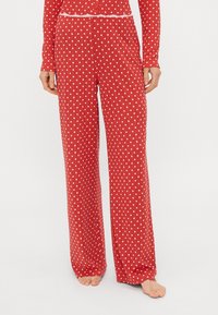 Rote Schlafanzughose mit weißen Pünktchen, im entspannten Schnitt, aus weichem Stoff, mit einem elastischen Bund und einer Spitzenakzentuierung.