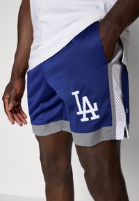 Blue mesh shorts with a white LA logo, gray accents, and side pockets. Features a breathable texture and contrasting hem design.