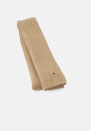 Écharpe beige en tricot côtelé pliée avec un petit logo rectangulaire rouge, blanc et bleu sur fond blanc uni.