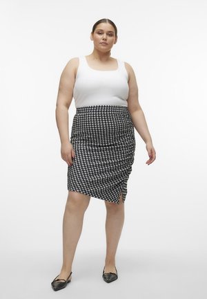 Witte tanktop gecombineerd met een zwart-wit houndstooth kokerrok met rimpelingen bij de taille. Zwarte flats maken de look compleet.