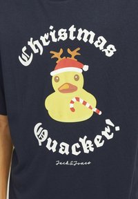 Marineblå t-shirt med en tegneserieand iført rensdyrhorn og en julesok, der holder en slikstok, med teksten "Christmas Quacker!"
