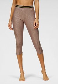 Leggings capri marroni con un sottile motivo leopardato, pannelli laterali texturizzati e una vita nera e oro. Materiale morbido e elasticizzato.