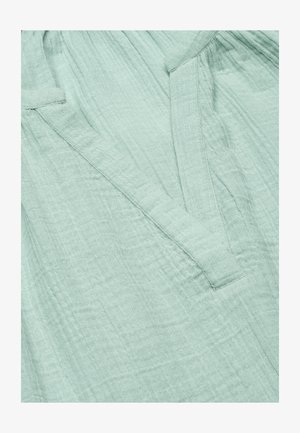 Hellgrüner strukturierter Stoff mit weichem, zerknittertem Muster und einfachem Stoff-Gürtelschlaufen-Detail.