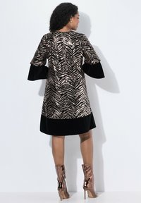 Musta ja kultainen paljetein koristeltu mekko, jossa on seepra kuvio, kellohihat ja kiinteä musta helma. Yhdistetty metallin värisiin korkokenkiin.