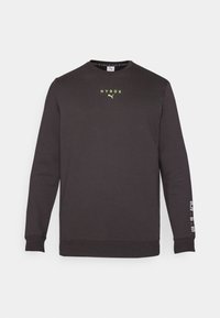 Svart hettegenser med lange ermer, rund hals, reflekterende gul "HYROX" logo på brystet og hvit tekst på venstre erme. Mykt, fleece-materiale.