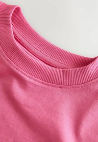 Pink cotton sweatshirt collar with ribbed texture, smooth body, and stitching detail visible on the edges.