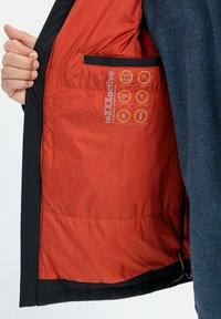 Wnętrze kurtki izolowanej z pomarańczowym wykończeniem. Posiada oznaczenia wodoodporności i oddychalności, czarne wykończenia oraz kieszeń na ręce.