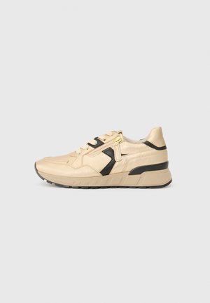Beige sneaker with black accent, side zipper, thick sole, and lace-up closure, shown in profile on a plain light gray background.