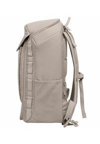 Sac à dos beige en tissu lisse, avec des bretelles rembourrées, fermeture éclair, poche latérale en mesh et design structuré.