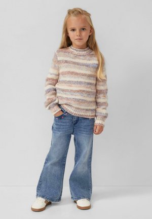 Texturierter Strickpullover in Pastellfarben mit horizontalen Streifen, kombiniert mit hellblauen, weiten Jeans und weißen Sneakers mit braunen Sohlen.