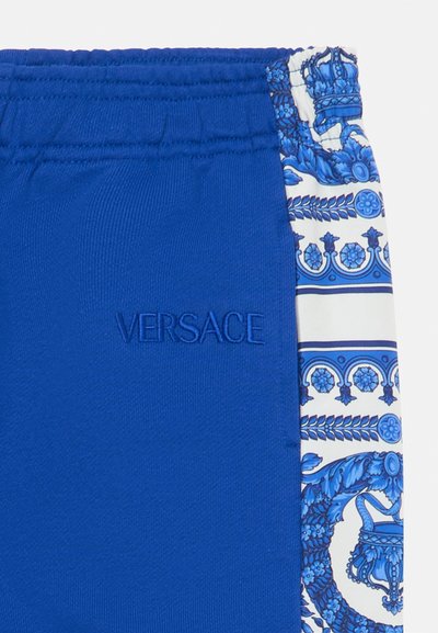 Blå shorts med elastiskt midjeband, som har en sidopanel med intrikata blå och vita mönster. "VERSACE" logotyp broderad i blått.