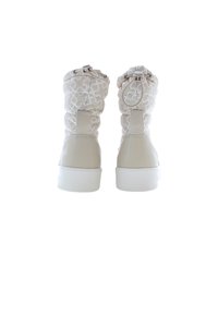 Stivaletti alla caviglia imbottiti beige con un motivo geometrico bianco, punta arrotondata e finitura lucida sul tacco. Presentano linguette per una facile calzata.