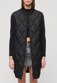 Czarna, pikowana bezrękawnik z zamkiem z przodu, z teksturowanym wzorem i bocznymi kieszeniami. Wykończony prążkowanym kołnierzem.