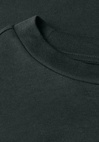 Detailní záběr na tmavě zelený žebrovaný límec s crew neck a strukturu látky na pleteném bavlněném oděvu.