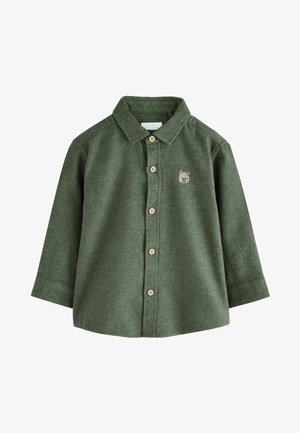 Zielona flanelowa koszula z długimi rękawami, z przodem na guziki i naszywką z niedźwiedziem na lewej piersi. Posiada brązowe guziki i klasyczny kołnierzyk.