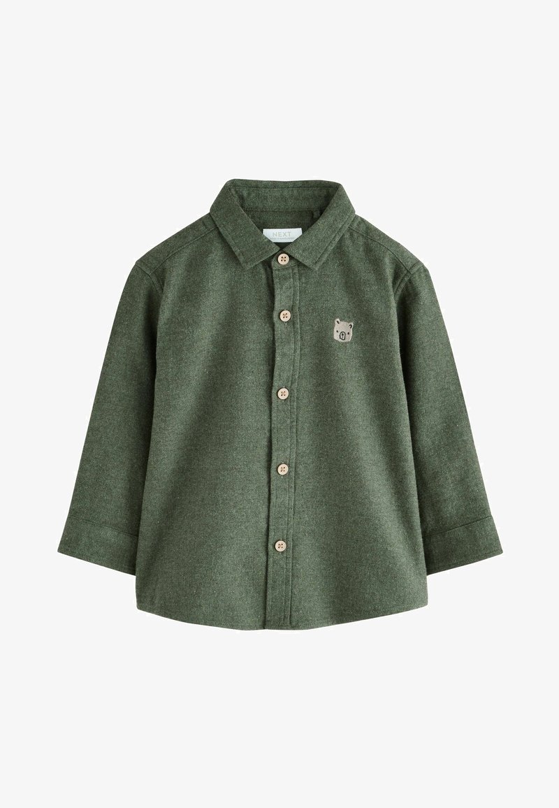 Zaļš flaneles krekls ar garām piedurknēm, pogu priekšpuse un lāča aizdare kreisajā krūtī. Iespējas: brūnas pogas un klasiskā apkakle.