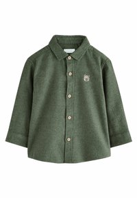 Camicia in flanella verde a maniche lunghe, con bottoni frontali e bottoni beige. Presenta un piccolo emblema di un orso sul lato sinistro del petto.