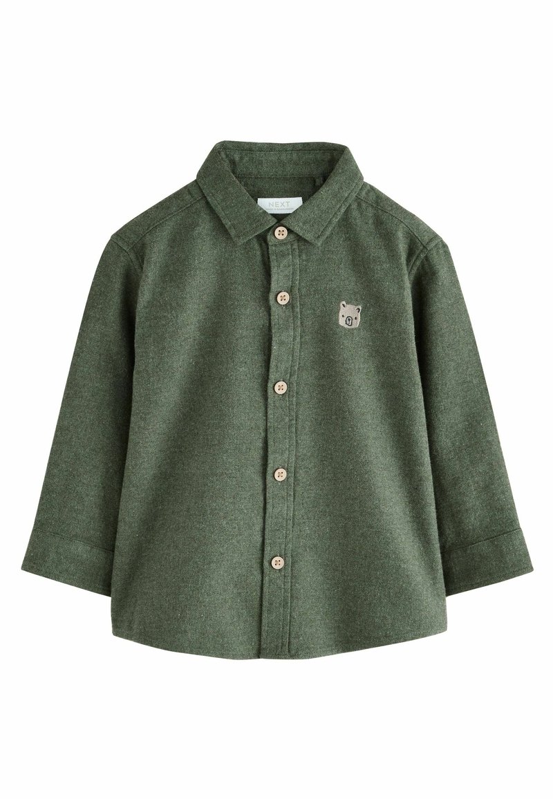 Camicia in flanella verde a maniche lunghe, con bottoni frontali e bottoni beige. Presenta un piccolo emblema di un orso sul lato sinistro del petto.