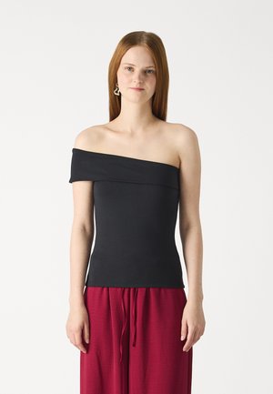 Top nero scollato realizzato in un tessuto morbido, design aderente, con una ampia scollatura. Abbinato a pantaloni rossi larghi con coulisse.