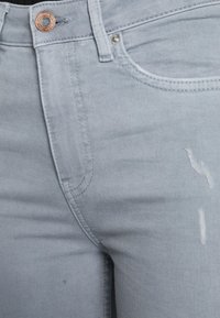 Vaqueros azul claro con una textura suave, que presentan un botón de cobre, un desgaste sutil y un diseño clásico de cinco bolsillos.