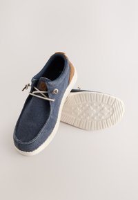Blaue Stoff-Slipper mit braunen Akzenten, weißer Gummisohle und strukturierter Oberfläche. Verfügen über elastische Schnürsenkel und markante Nahtdetails.