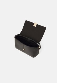 Geantă de mână din piele neagră cu un închizător aurie, de formă rectangulară și cu un singur mânere. Interiorul prezintă un căptușel întunecat cu buzunare de organizare.