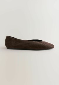 Ballerina in suede marrone con punta affusolata, posata su uno sfondo chiaro, che mette in evidenza un design elegante e minimalista.
