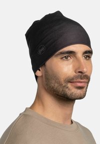 Black knit beanie with a smooth texture, featuring a subtle logo tag. The hat sits snugly on the head, covering the ears.