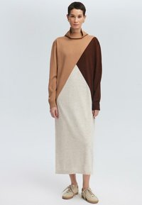 Robe pull longue dans des blocs de couleur marron, beige et gris clair ; présente un col haut et des détails côtelés au niveau des poignets.