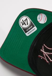 Cappellino da baseball regolabile con esterno nero, visiera verde, cuciture bordeaux e dettagli del logo ricamati. Include etichette del marchio.