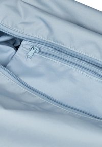 Helles blaues Innenfutter eines Stoffbeutels mit glatter Textur, ausgestattet mit einer Reißverschlusstasche und einem Reißverschluss. Mehrere sichtbare Nahtdetails.