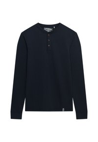 Camisa henley de manga larga en color azul marino, hecha de algodón suave, con tres botones marrones en el cuello y una pequeña etiqueta de logo en el dobladillo.