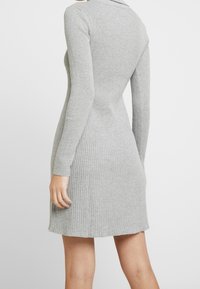 Gray ribbed sweater dress with long sleeves, fitted silhouette, and a slight flare at the hem. Textured fabric and subtle neckline details.