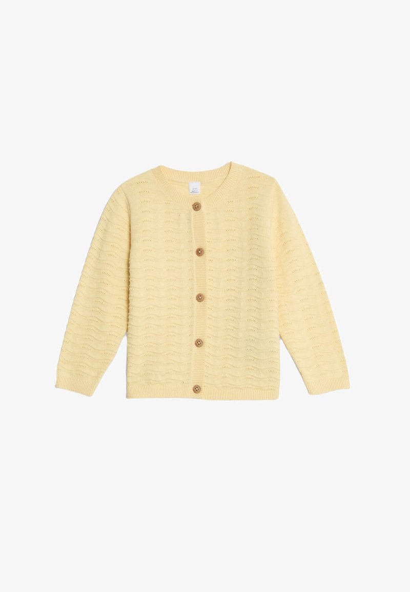 Cardigan giallo a maglia con un motivo a onda, maniche lunghe e cinque bottoni in legno sulla parte anteriore. Polsini e orlo a costine.