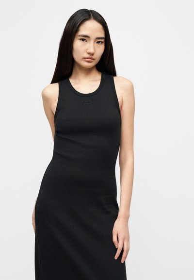 Μαύρο ριμπ φόρεμα τύπου τοπ με εφαρμοστή σιλουέτα, στρογγυλή λαιμόκοψη και διακριτική λεπτομέρεια με λογότυπο στο στήθος. Απαλό, ελαστικό ύφασμα.