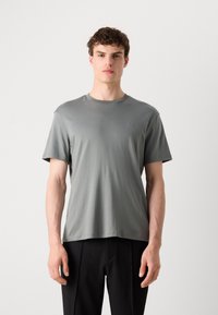 Tricou gri cu mânecă scurtă, dintr-un material neted și ușor. Dispune de un guler de tip crew și detalii subtile ale logo-ului pe piept.