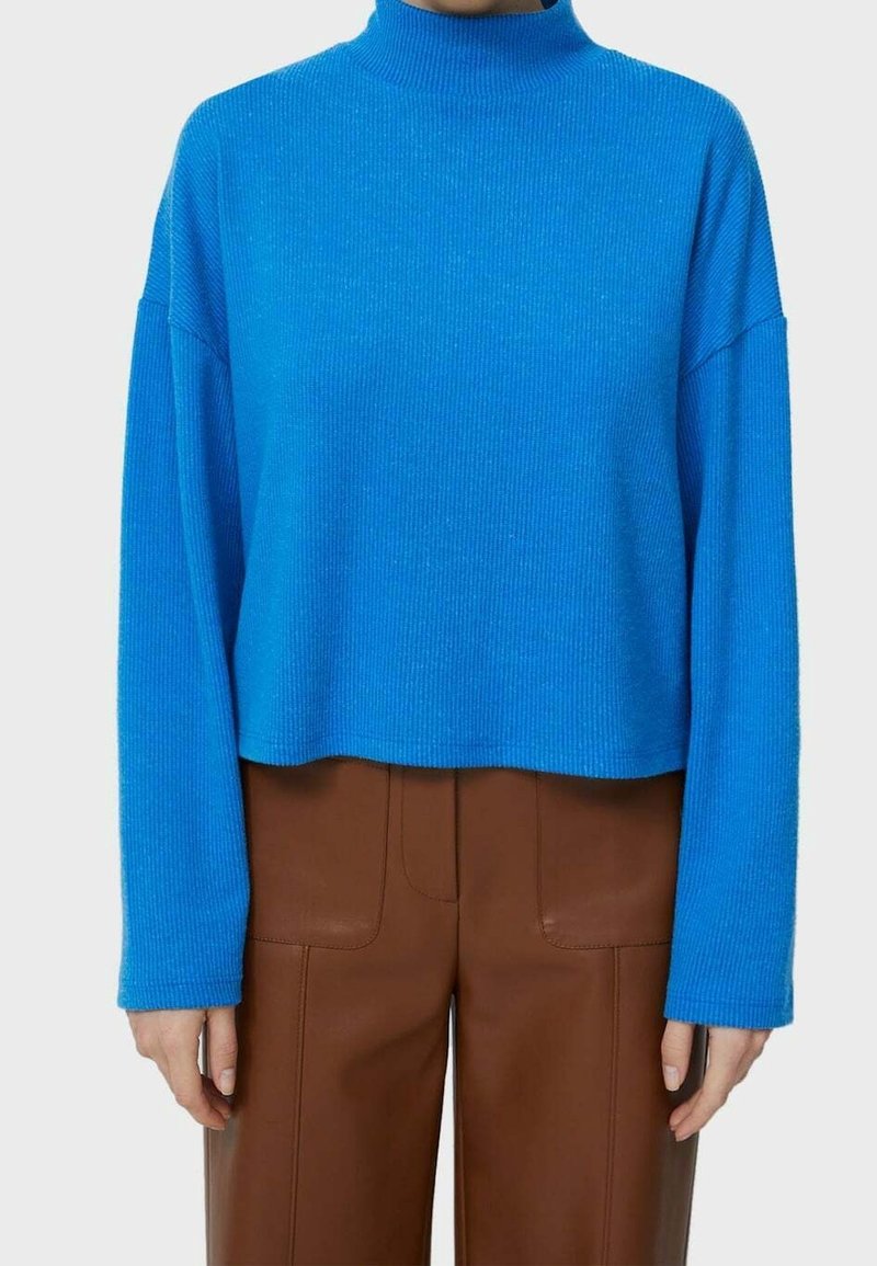 Maglione a collo alto cropped e a costine di un vivace blu, con maniche lunghe e una finitura texturizzata. Abbinato a pantaloni in ecopelle marroni.