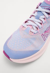 Chaussure de course légère en bleu pastel et rose. Présente un tissu texturé, des panneaux en maille et un bout prononcé avec une semelle extérieure violette.