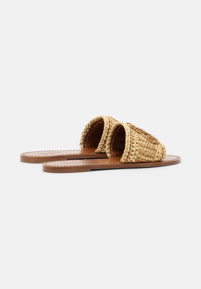 Paire de sandales plates en cuir marron avec larges brides en paille tissée sur un fond blanc.