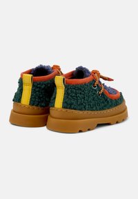 Grünes, gepolstertes Schuhwerk mit einem orangefarbenen Akzent, gelber Fersenschlaufe und gemusterten Schnürsenkeln. Verfügt über eine klobige braune Sohle und eine strukturierte Oberfläche.