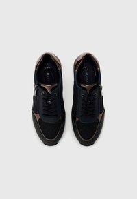 Baskets noires et brunes avec une finition texturée, un design à lacets, une fermeture éclair sur le côté et de subtils accents de paillettes sur le matériau supérieur.