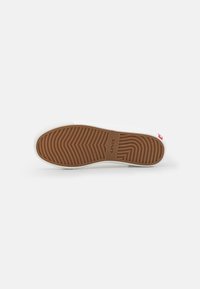 Les sneakers Levi's présentent une semelle en caoutchouc blanche avec un motif en zigzag et une semelle extérieure marron. Logo de la marque embossé sur la semelle, design minimaliste.