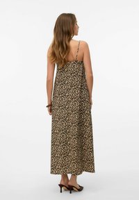 Robe maxi en imprimé léopard, dotée de fines bretelles ajustables, d'un tissu fluide et d'une coupe ample qui descend jusqu'aux chevilles. Sandales à talons marron.
