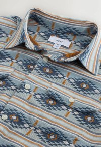 Kariertes Hemd mit einer türkisfarbenen Basis und geometrischen Mustern in Blau, Orange und Beige. Mit Kragen, zwei vorderen Taschen und Knöpfen.