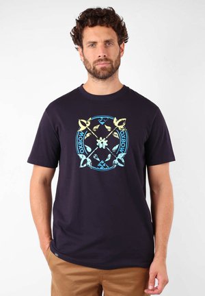 T-shirt navy en coton, avec un design graphique circulaire en jaune et bleu, ornée d'oiseaux stylisés et de formes géométriques.